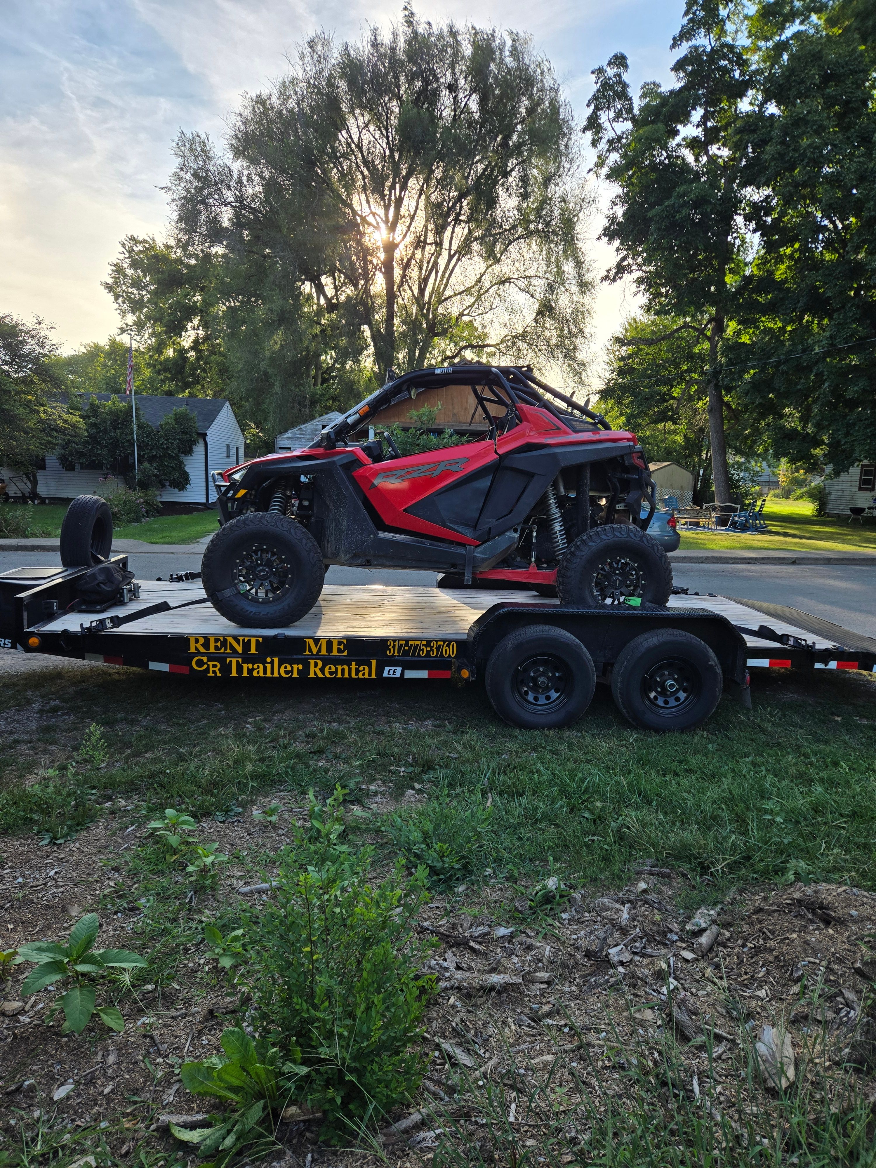 Red UTV side-by-side on CR Trailer Rental flatbed trailer for recreational vehicle transport in Greenfield, IN